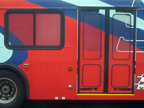 a blue red and white bus is parked on the side