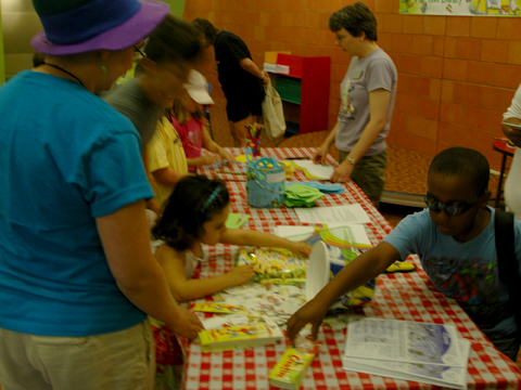 children standing and sitting around paper plates on a table