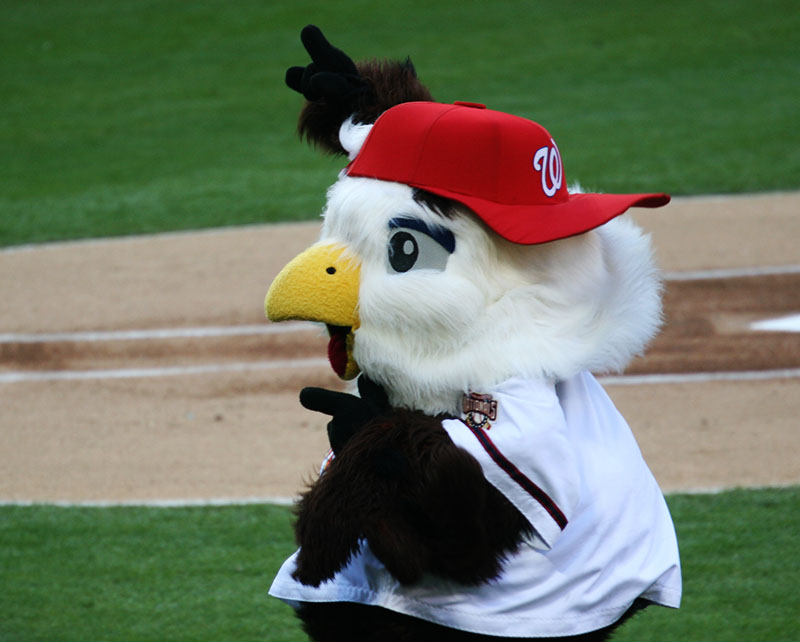 a mascot stands at the ready on a baseball diamond