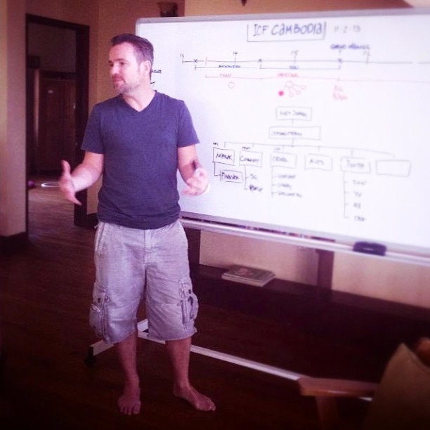 a man in a black shirt and gray shorts giving a presentation