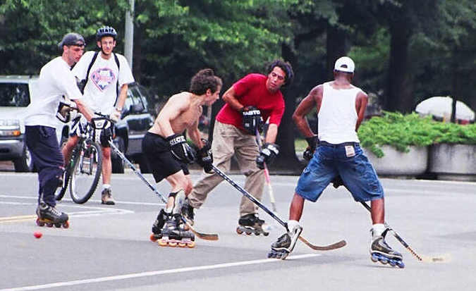 a group of young men playing a game of roller blade hockey