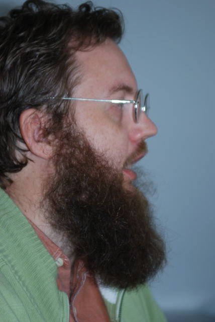 a bearded man with glasses looking off to the side