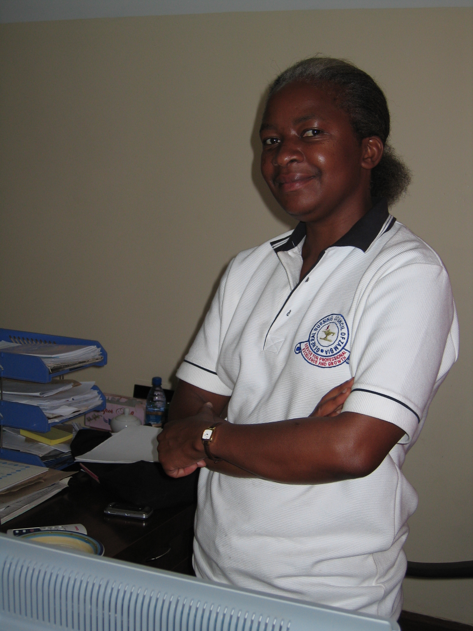 a woman with a white shirt and white hair stands by her table