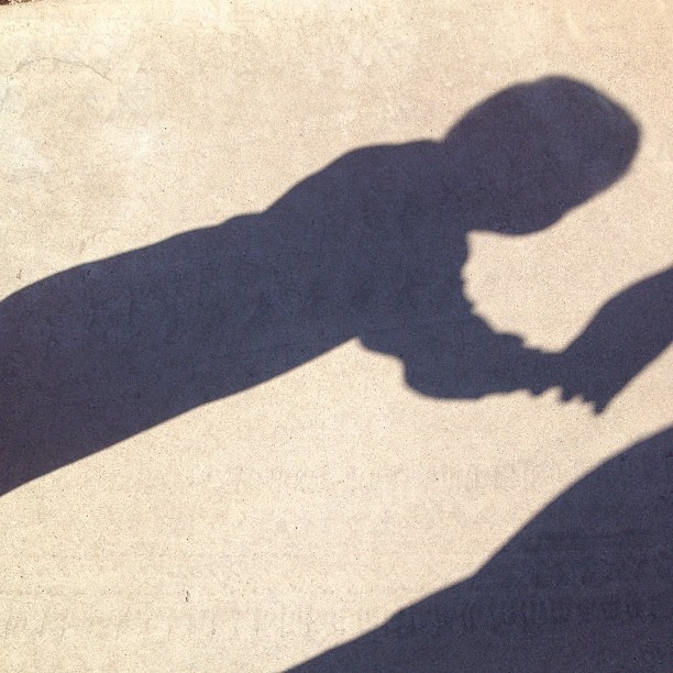 shadow from a man on the ground holding a skateboard