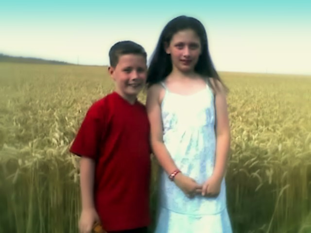 two little boys are standing by the wheat field
