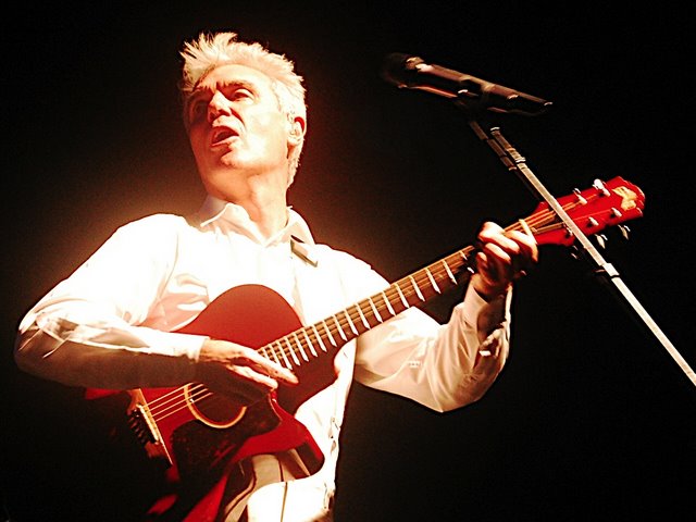 a man holding a red guitar singing into a microphone