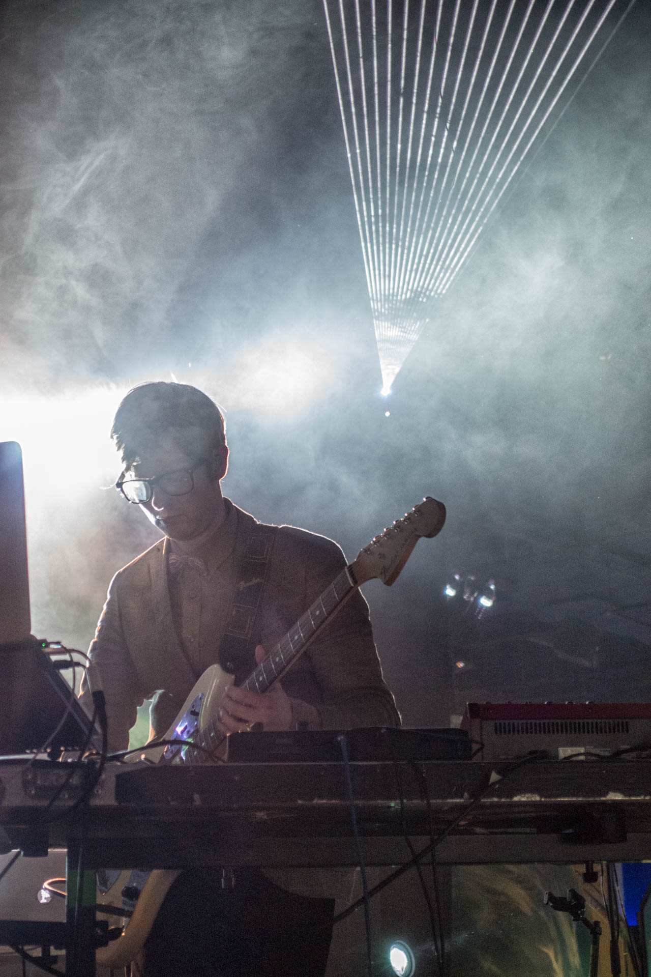 man wearing headphones and playing guitar on stage