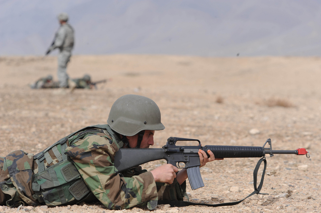 an army soldier with a machine gun lying on the ground