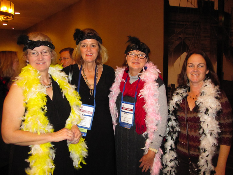 group of women wearing feather boa'd posing for a po