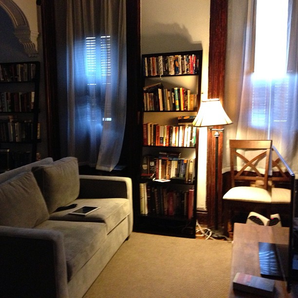 a room with a couch, chair and book shelf