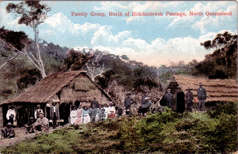 a group of people standing outside of a log hut