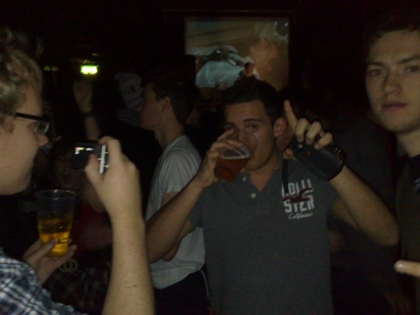 a group of men standing in a room holding onto beer glasses