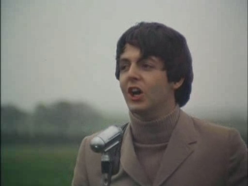 a man in suit and turtle neck singing into a microphone