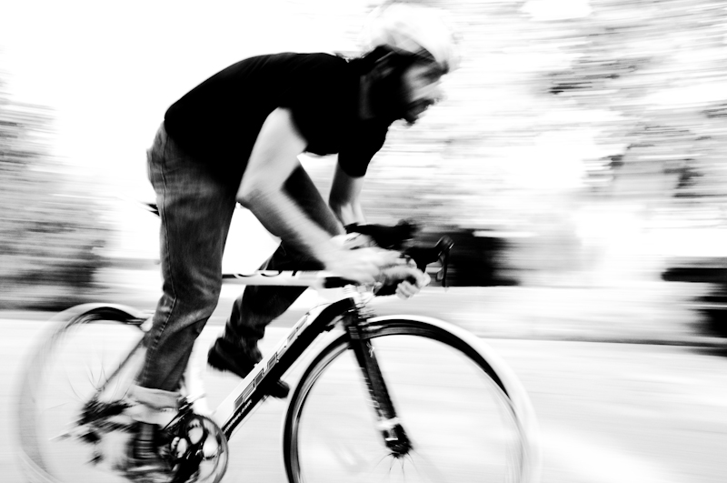 man riding his bicycle in motion in the street