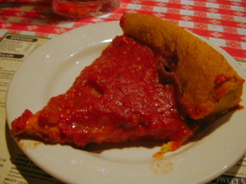 the plate holds an enormous piece of deep dish pizza