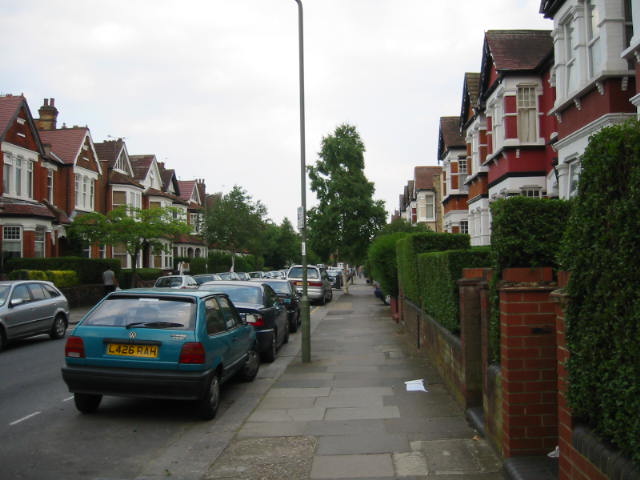cars parked along the street with brick sidewalks and grass