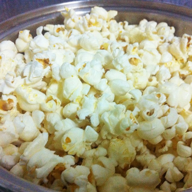 popcorn kernels in a metal bowl with blue tins