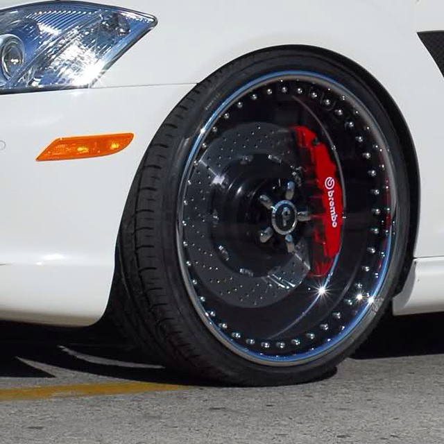 car with black wheels and red tire cover sitting next to curb