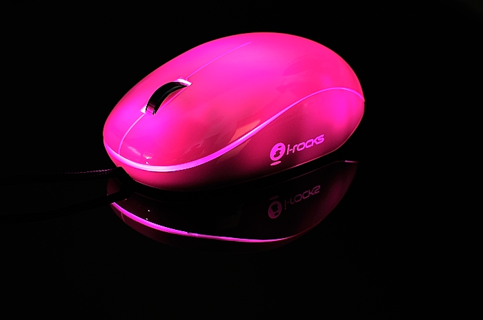 a pink mouse sitting in the dark with its light on