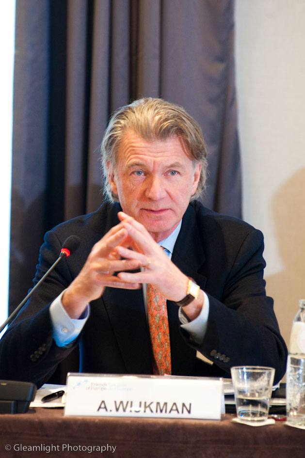 an older man is sitting at a table speaking