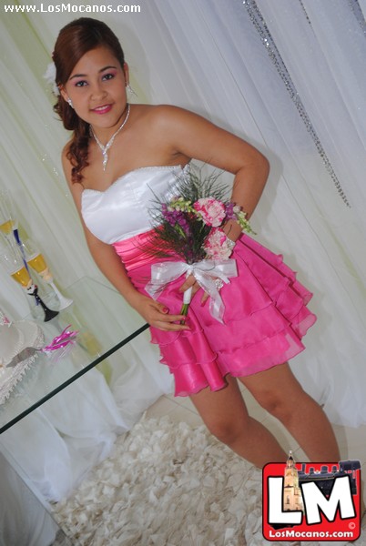 a young lady with a wedding bouquet standing in a pink dress