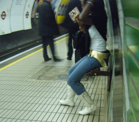 a woman sitting on a bench while waiting for the subway