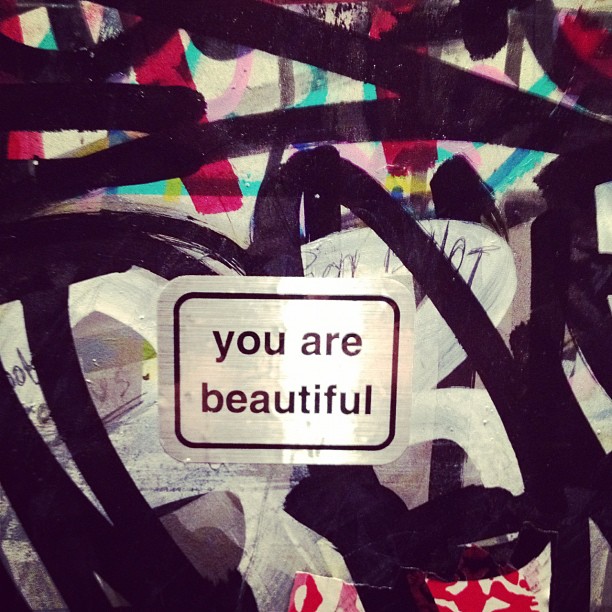 an abstract piece of art painted with spray paints and with graffiti the caption you are beautiful