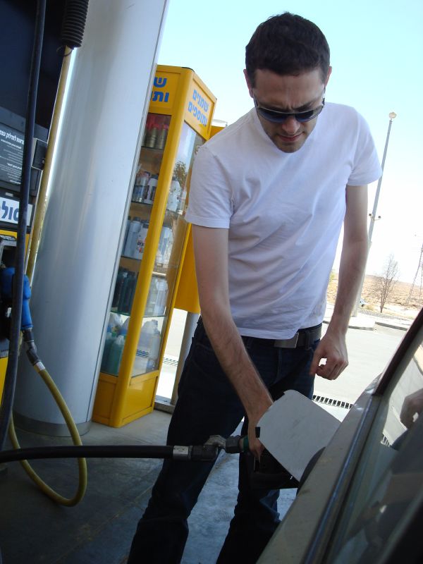 man filling gas into his car at a gas station