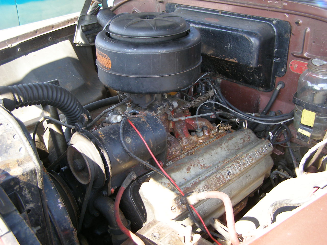 a vehicle engine with the hood up and a large black cap on
