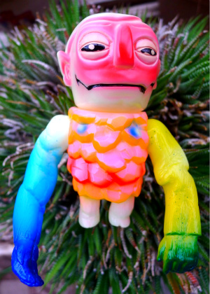 a very colorful hand - made figure next to some plants