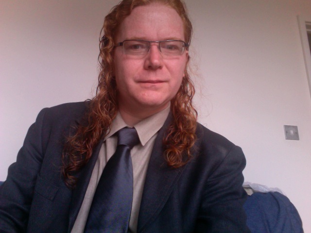 a young lady with red curly hair wears a suit and tie