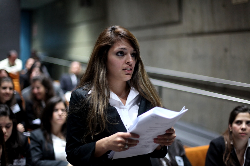 a woman in black blazer holding up a paper