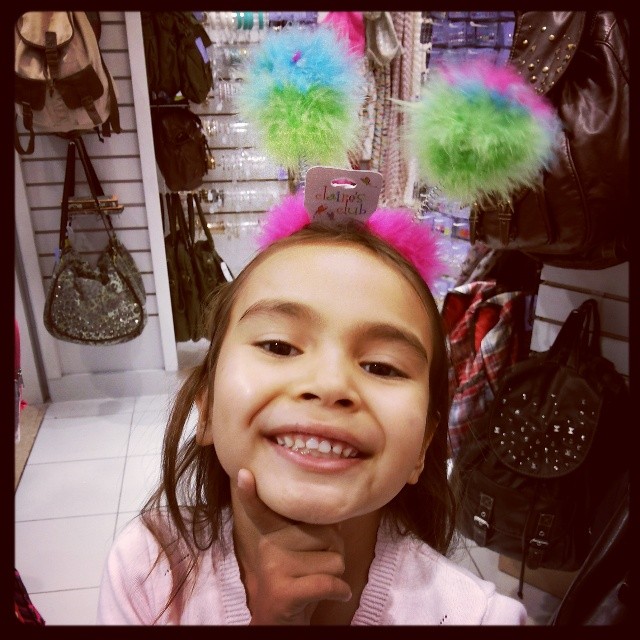 a child with a bright hair bow and pompoms on her head