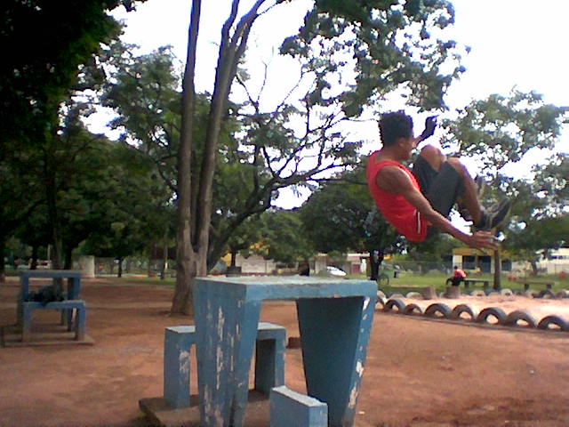 a guy on a skateboard in the air next to two cement benches