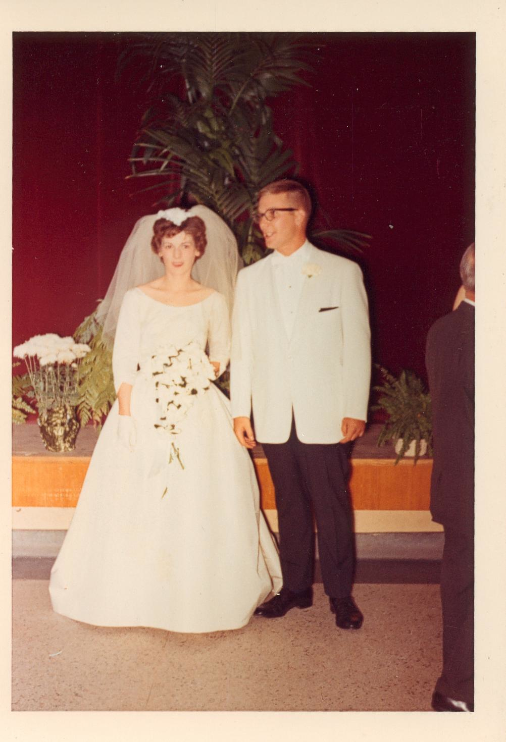 a man in a suit and tie is standing next to a woman wearing a dress