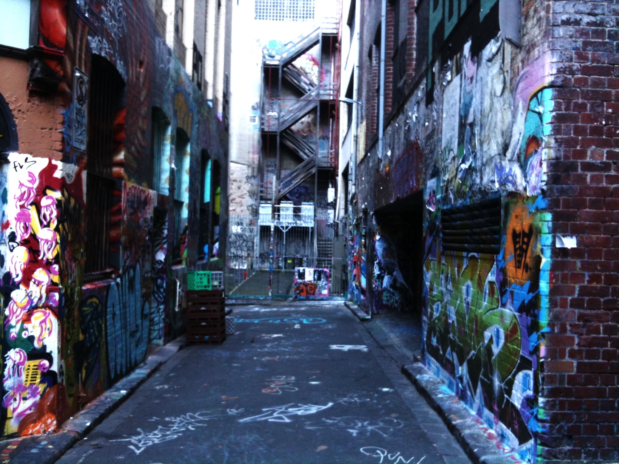 an alley with a walkway and many different colored graffiti on the walls