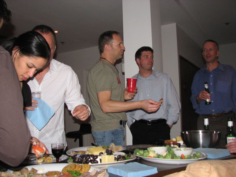 group of men standing around table with plates and drinks