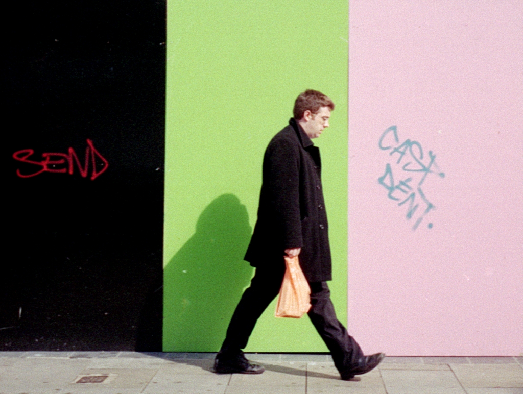 a man walking past a wall that has graffiti