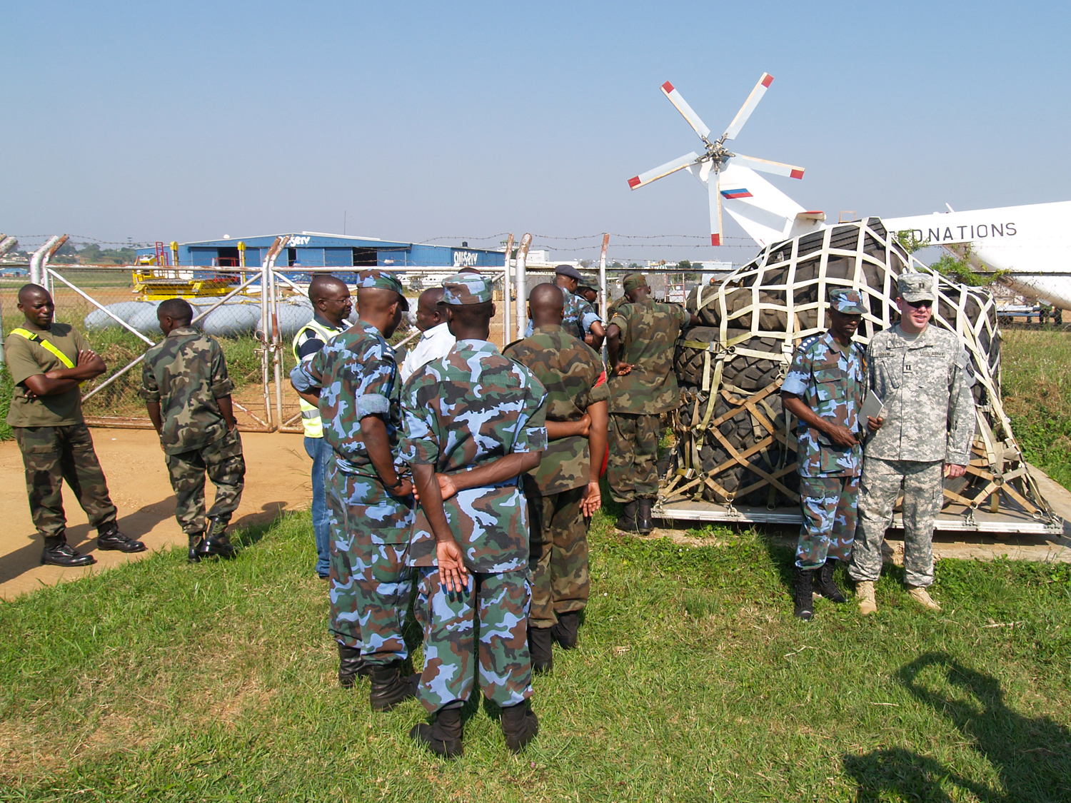 men in camouflage uniforms and one man standing with a large object