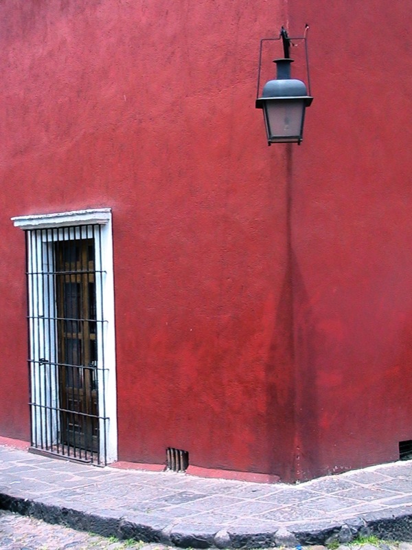 the cat is sleeping on the curb in front of the red building