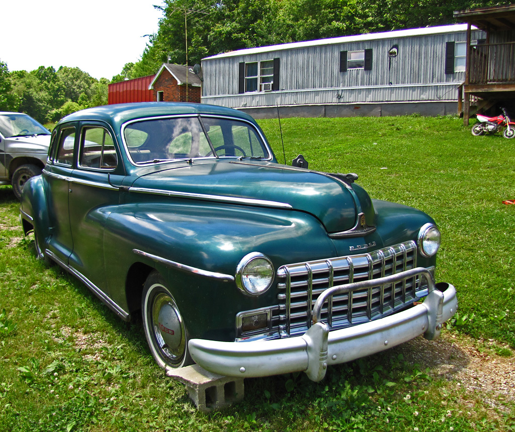 a green classic car sitting in a grassy field