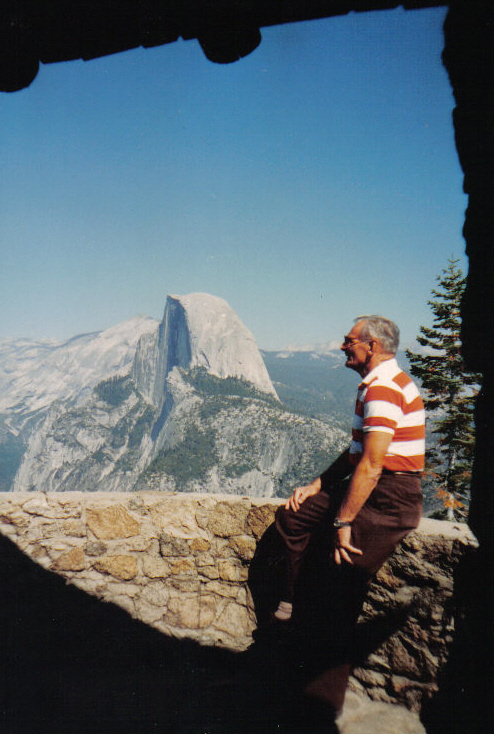 a man is on the ledge looking out over a valley