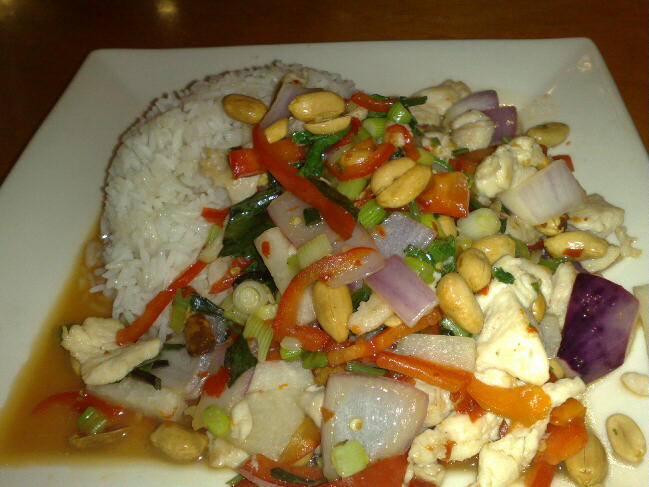 chicken, rice, and vegetables on a plate with a white sauce