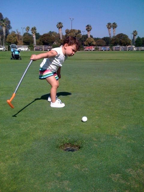 a child hitting a golf ball with a club