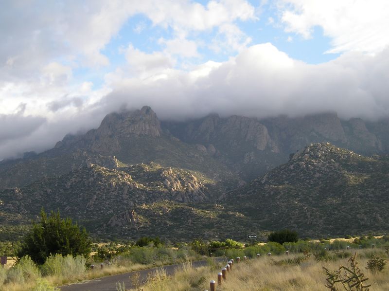 mountains are behind a road that is covered with grass