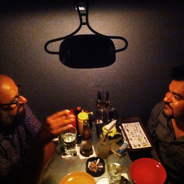 two men sitting at a table with plates and glasses