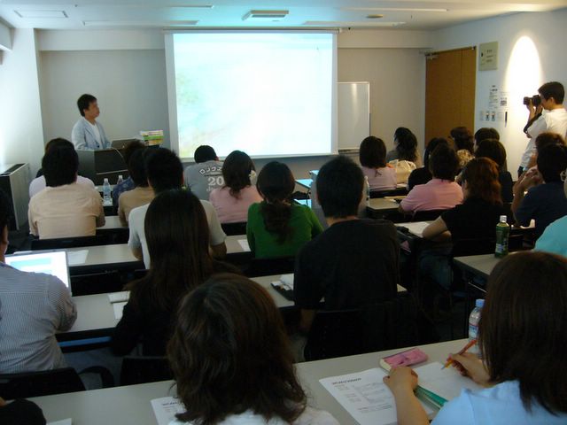 a classroom full of students and one man giving a presentation