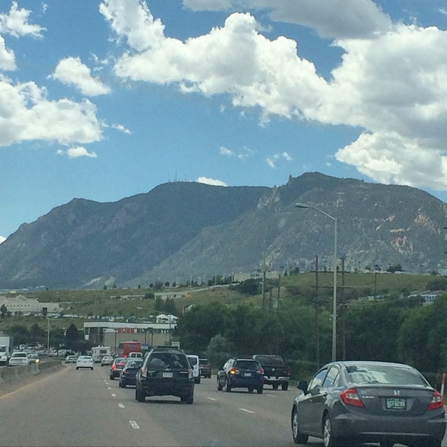 cars driving down a road with mountains in the background