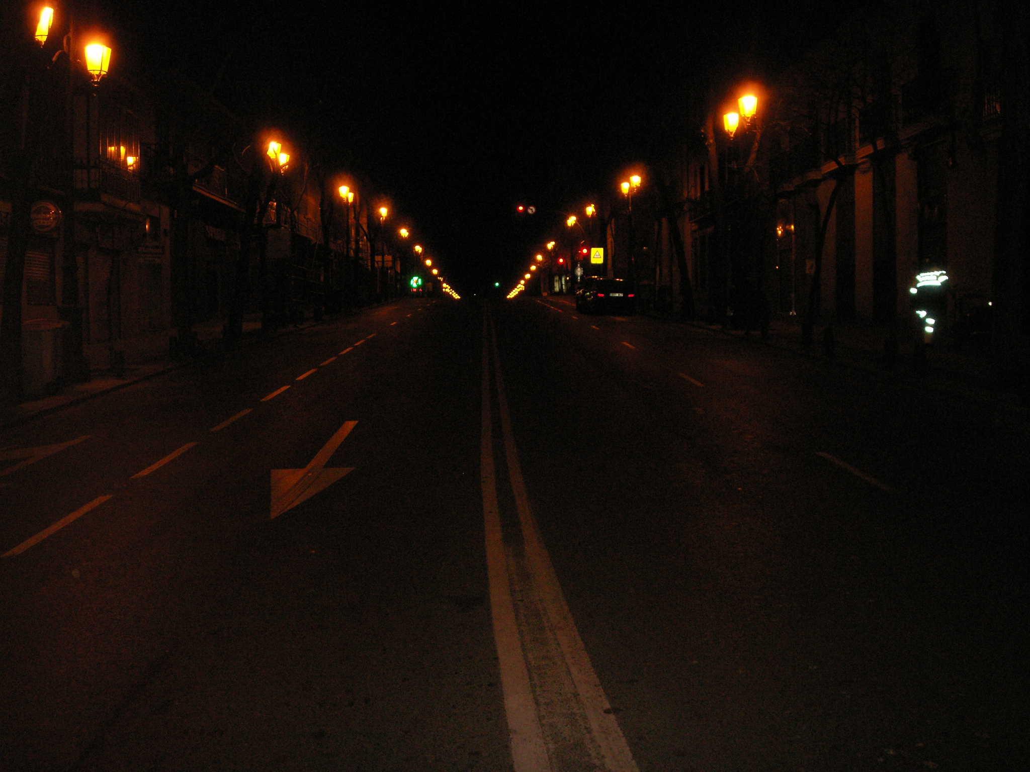 an empty city street is pictured at night with lights on