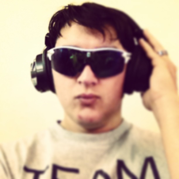 a man wearing headphones and sunglasses holding up headphones
